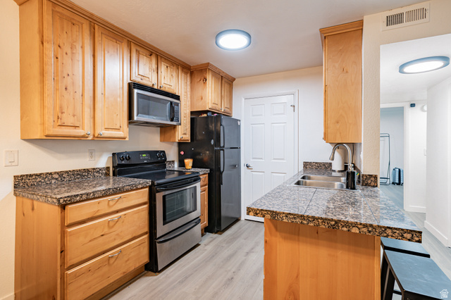 1221 Waterside Cove, Unit 11 Midvale, UT 84047 - Photo 6 of 23 Kitchen featuring wood cabinetry, mottled countertop surfaces, stainless steel appliances, and wood-finish flooring