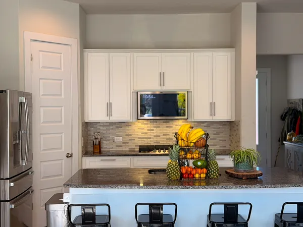 a kitchen with stainless steel appliances a stove a refrigerator and a dining table with wooden floor