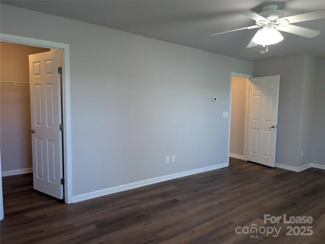 an empty room with wooden floor and a ceiling fan