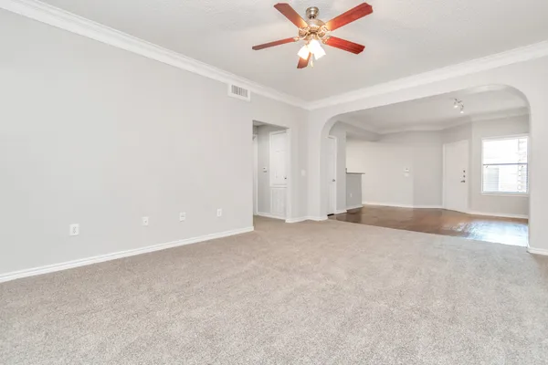 an empty room with windows and fan chandelier fan