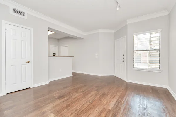 an empty room with wooden floor and windows