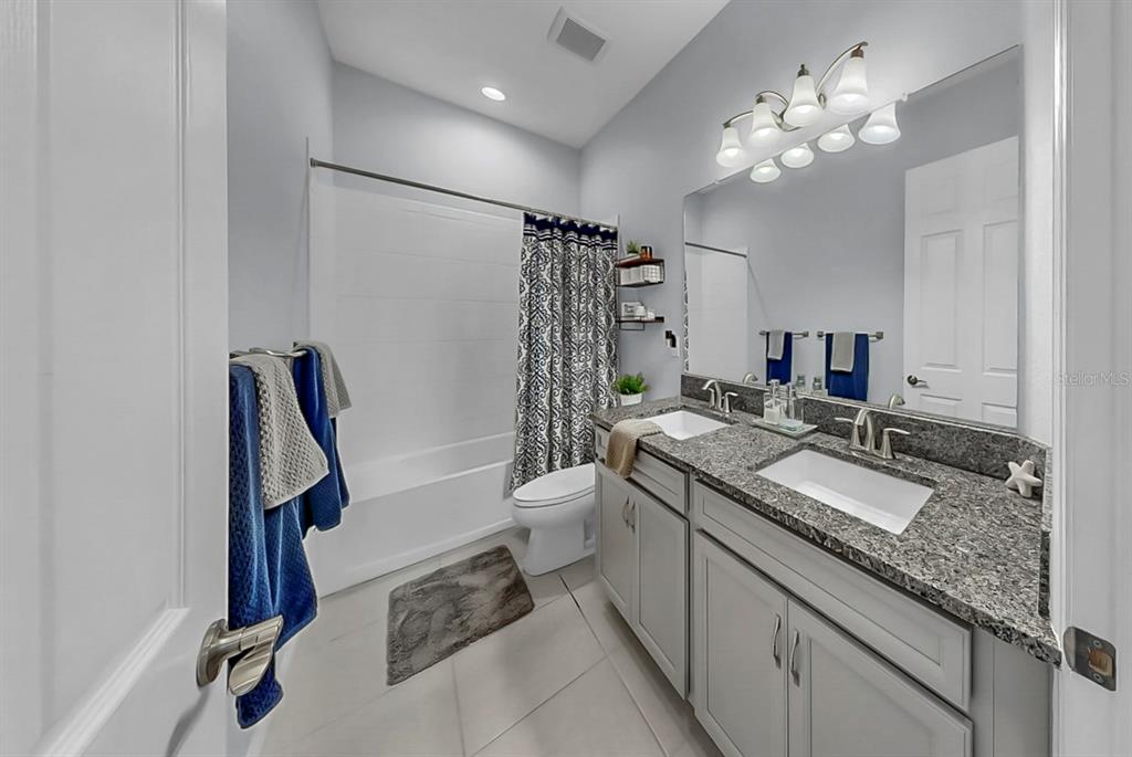 7709 Paradiso Drive Apollo Beach, FL 33572 - Photo 51 of 64 a bathroom with a granite countertop sink a toilet a mirror a vanity and shower
