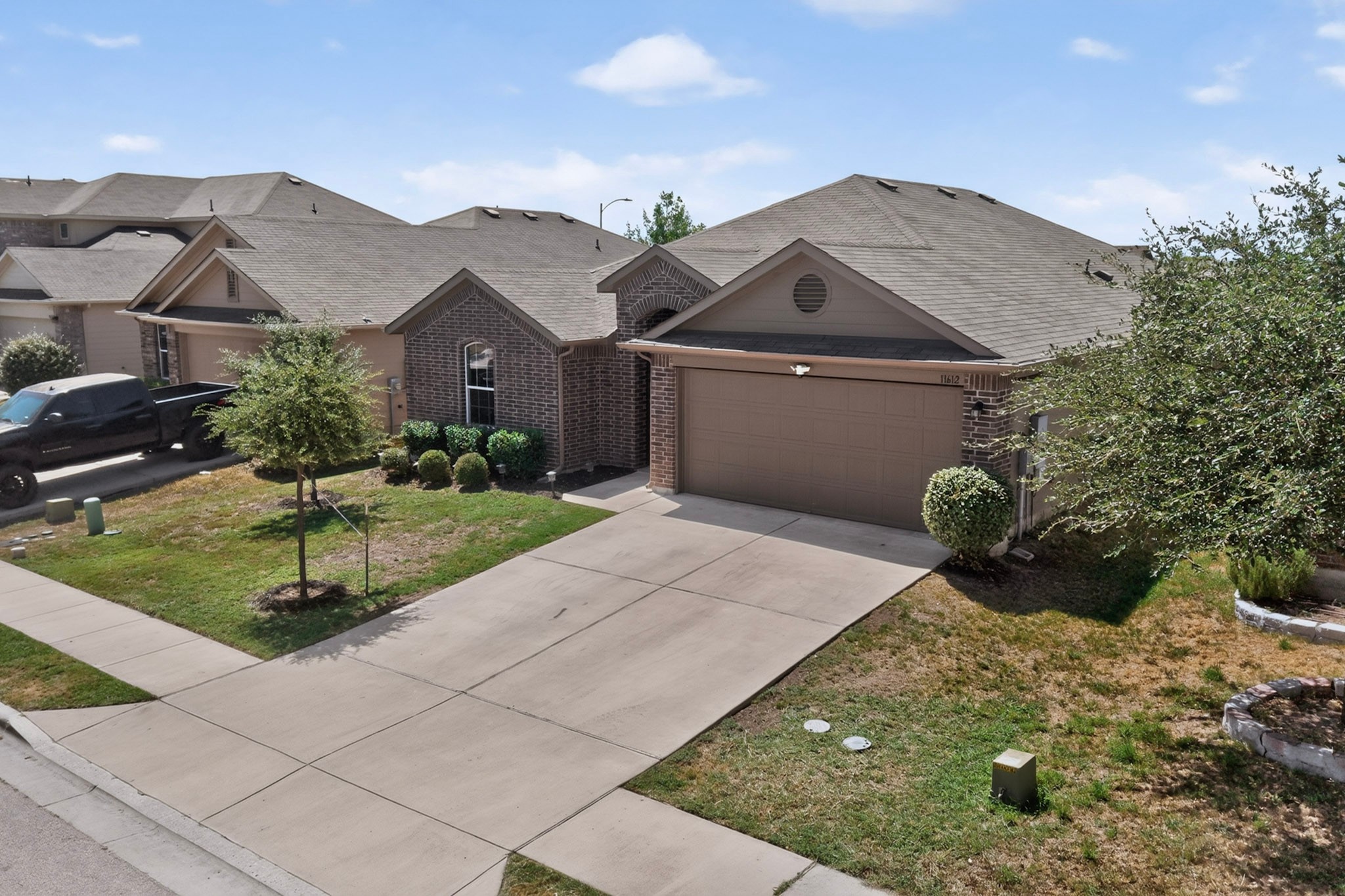 11612 Andesite Road Manor, TX 78653 - Photo 3 of 40 A spacious driveway leads to the front-facing garage of this modern brick-accented home.