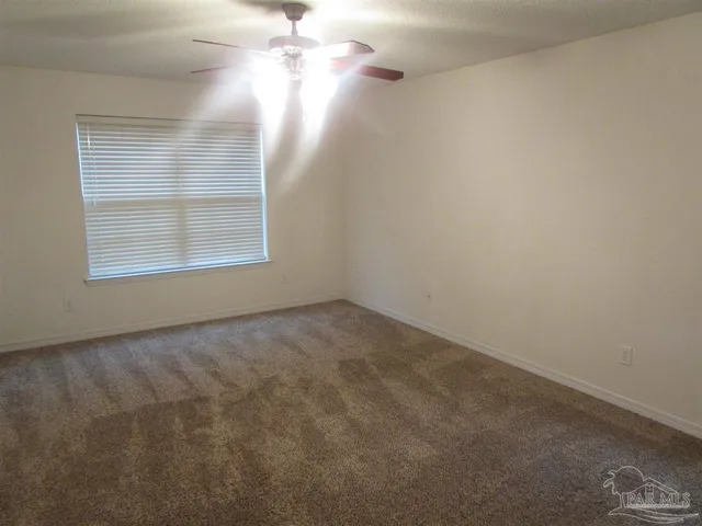 en empty room with windows and chandelier fan