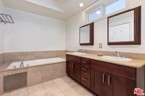 a spacious bathroom with a tub double sink and mirror