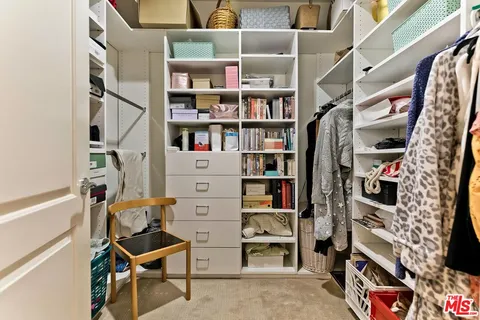 a view of walk in closet with clothes and shoes