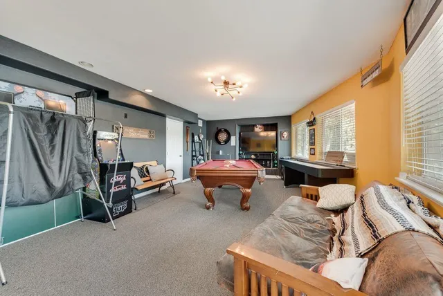 a living room with furniture pool table and windows