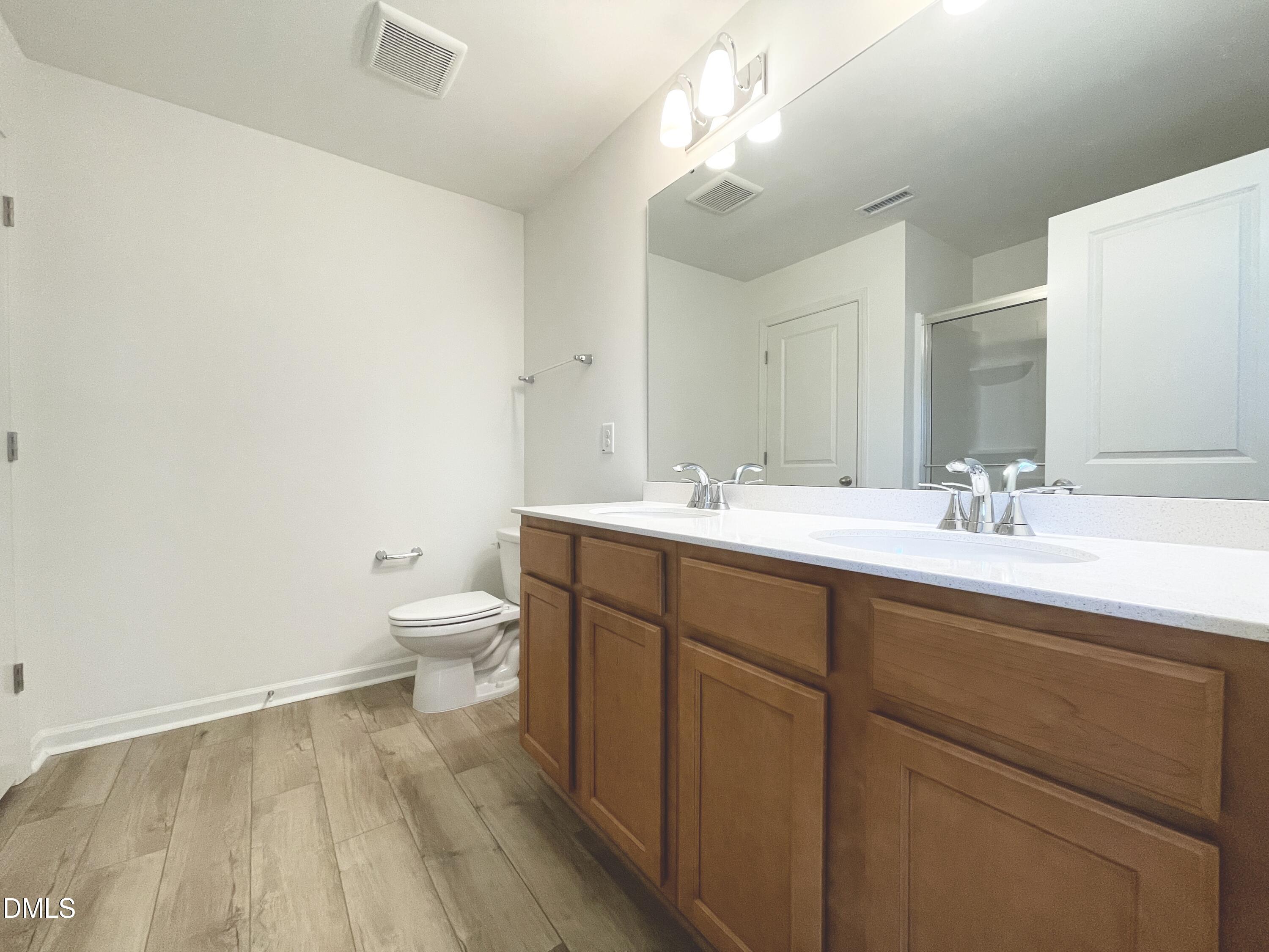 6117 Oak Psge Drive Raleigh, NC 27603 - Photo 15 of 25 a bathroom with a double vanity sink toilet and a mirror
