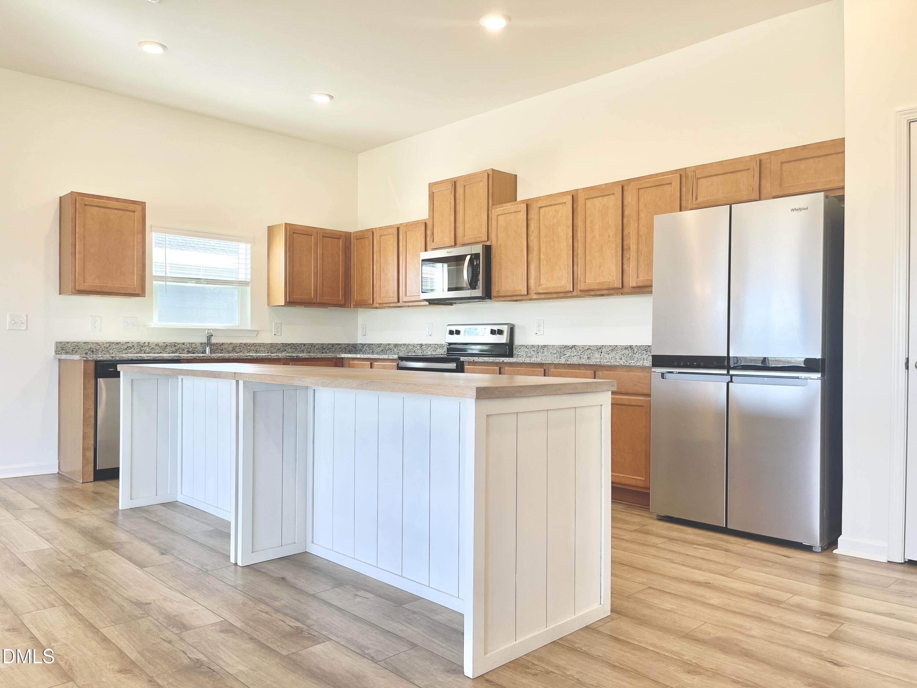 6117 Oak Psge Drive Raleigh, NC 27603 - Photo 7 of 25 a kitchen with granite countertop a refrigerator a stove and white cabinets with wooden floor