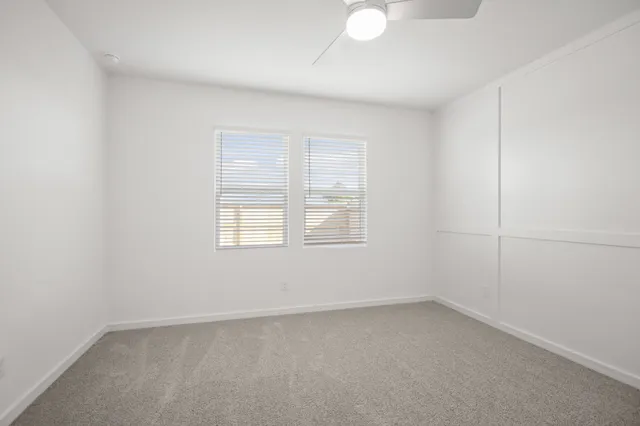 an empty room with a window and a fan