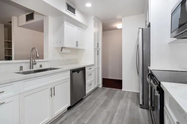 a kitchen with granite countertop a refrigerator and a stove top oven