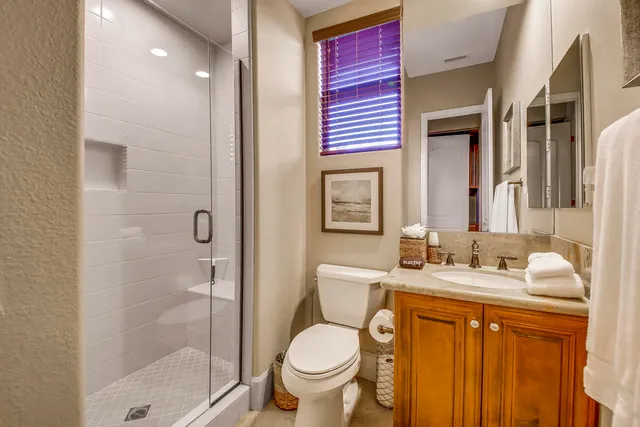 a bathroom with a granite countertop sink toilet mirror and shower
