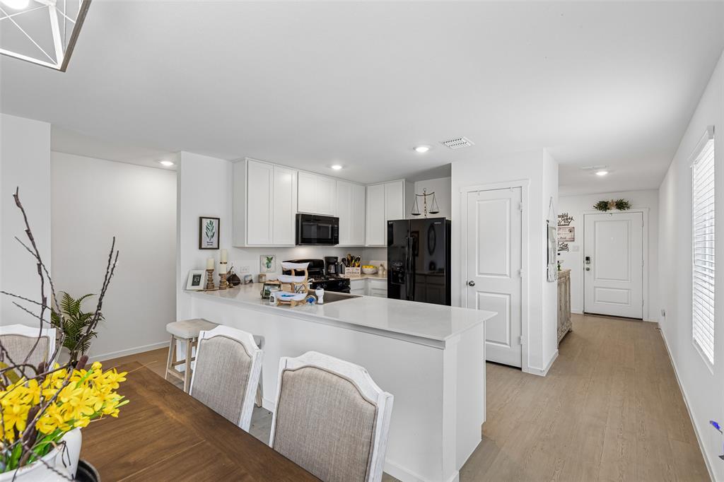 14163 Kempt Drive Pilot Point, TX 76258 - Photo 5 of 29 Designed with both style and functionality in mind, the kitchen offers timeless white cabinetry, generous counter space, recessed lighting, and a large island with seating—perfect for hosting guests or staying connected while preparing meals.