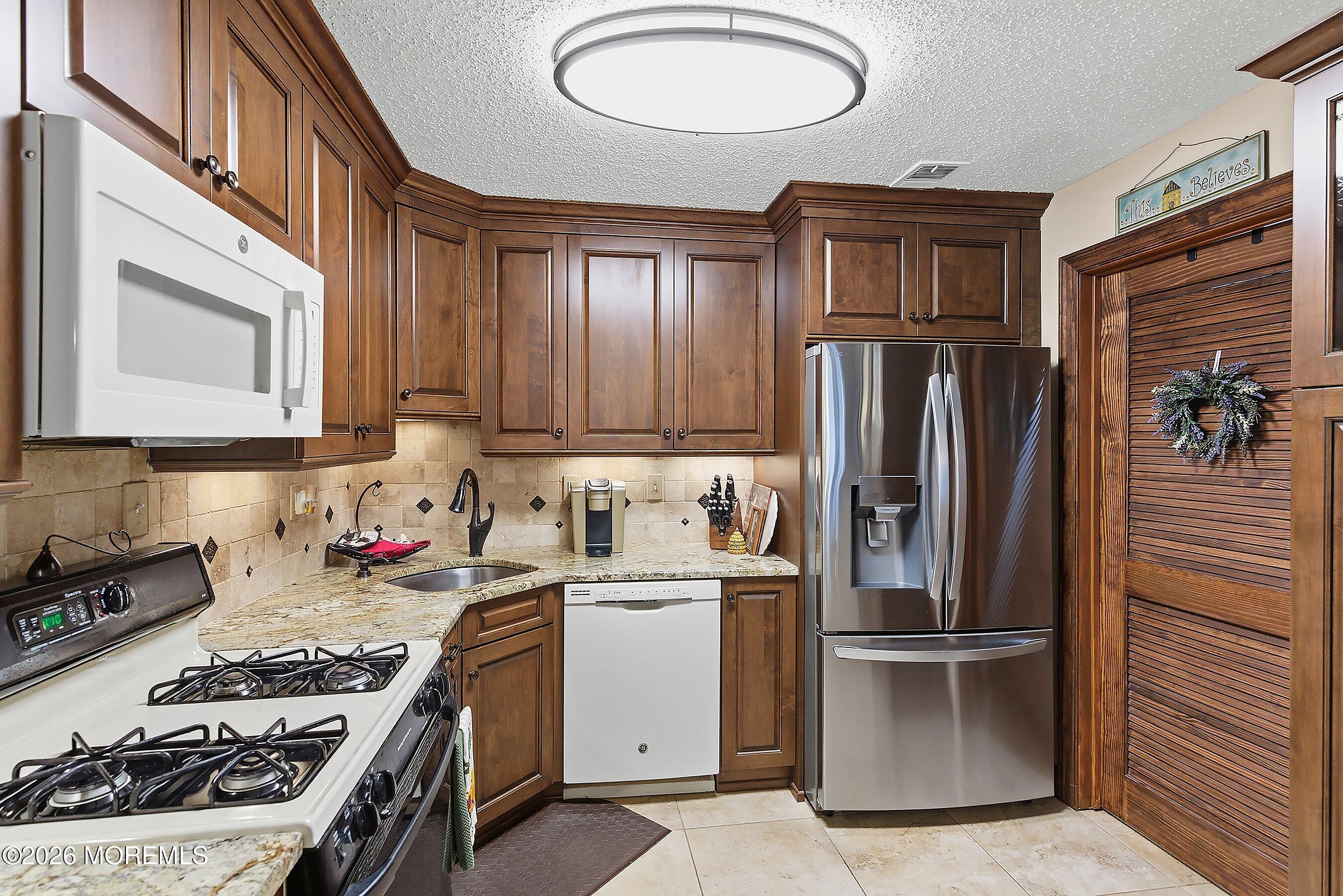 8-2 Seattle Court Freehold, NJ 07728 - Photo 12 of 35 a kitchen with stainless steel appliances granite countertop a refrigerator stove and sink