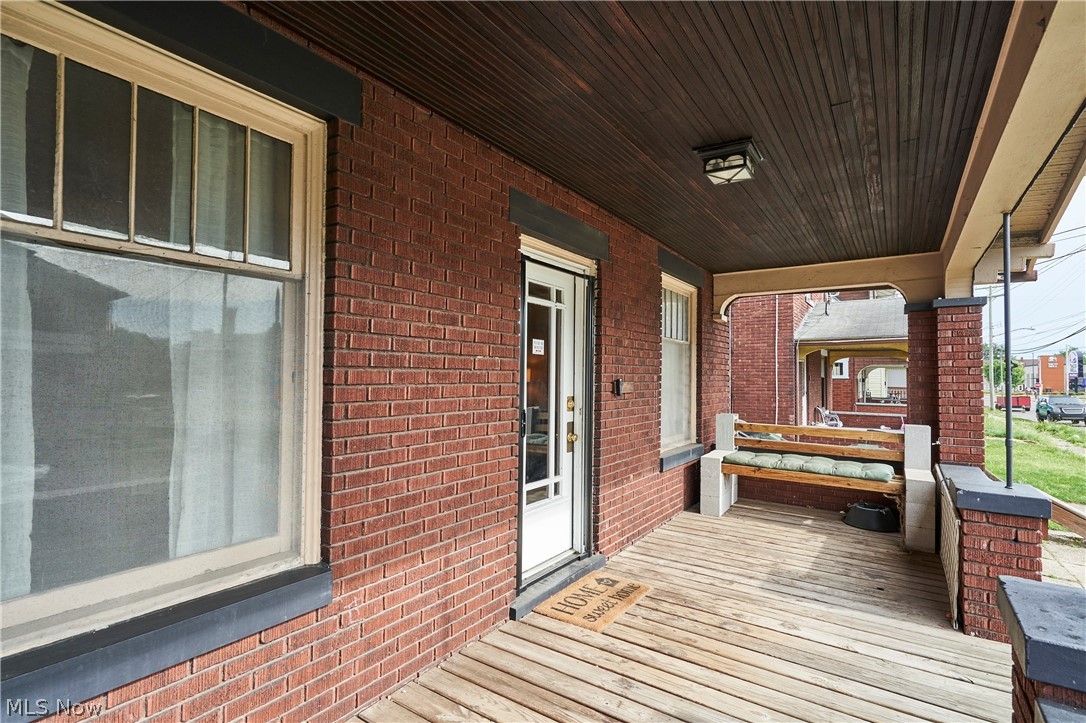 136 Smith Avenue Northwest Canton, OH 44708 - Photo 17 of 19 Brick exterior featuring a covered wood-plank porch with a wood-finish ceiling, decorative columns, and a front entry door with glass paneling