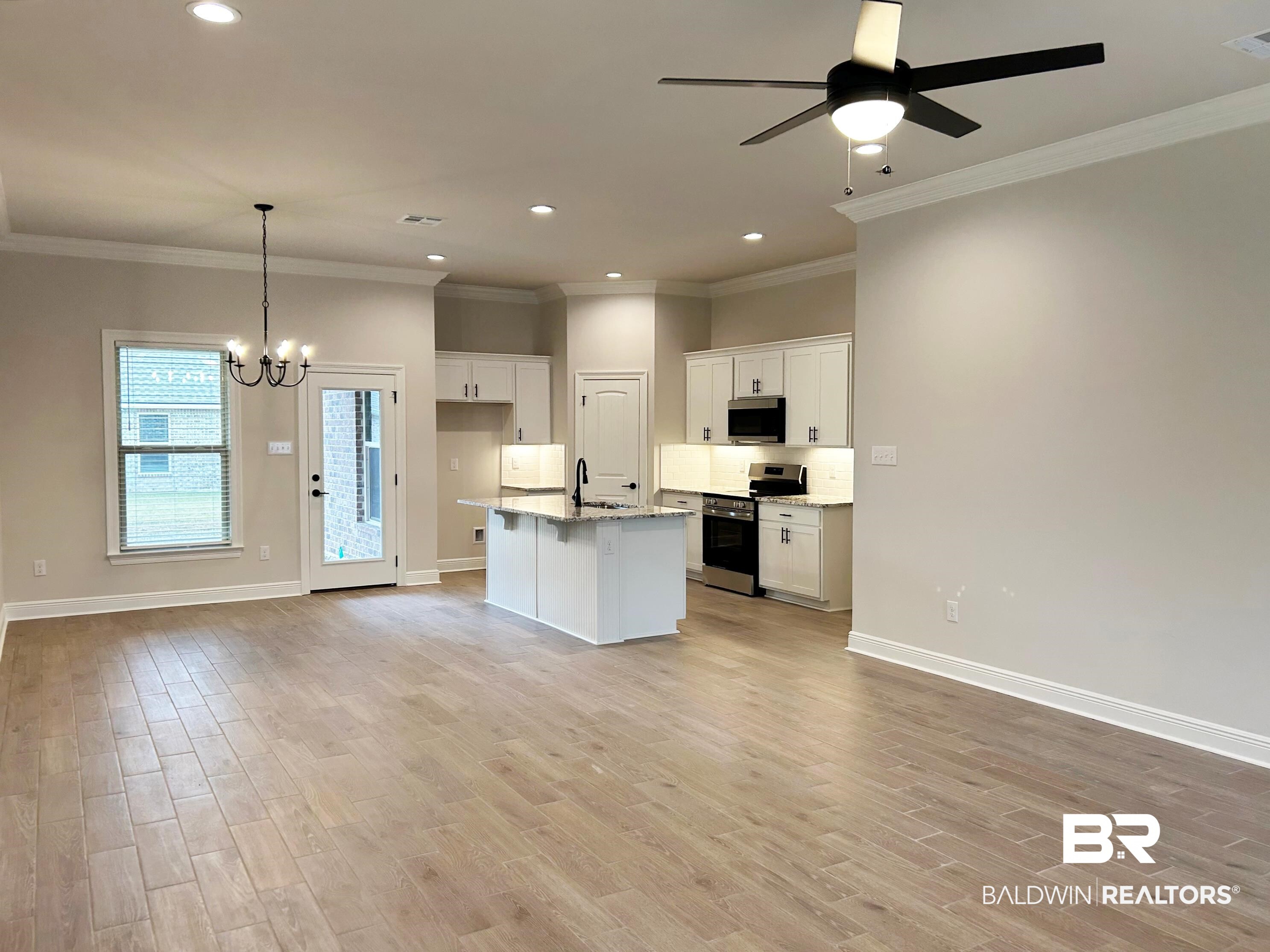 873 Sumter Loop Foley, AL 36535 - Photo 25 of 26 Kitchen featuring white cabinets, open floor plan, stainless steel appliances, a chandelier, and a center island with sink