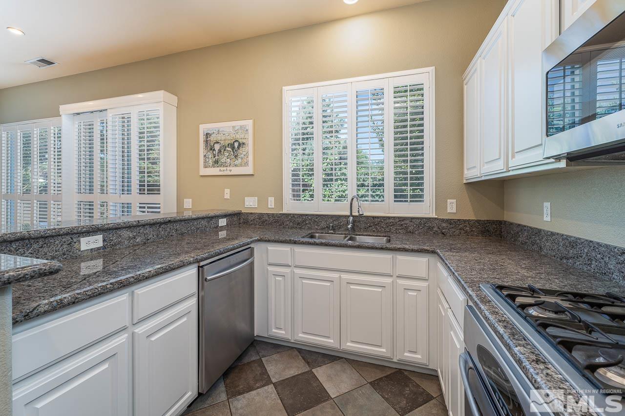 10617 Eagle Falls Way Reno, NV 89521 - Photo 10 of 30 a kitchen with granite countertop a sink stainless steel appliances white cabinets and a window
