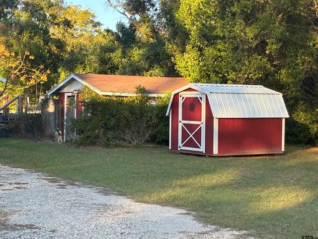 a view of a backyard with large trees and a barn