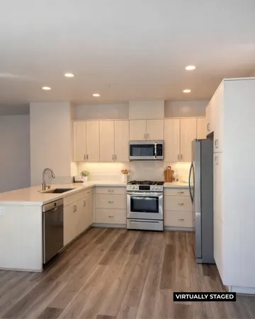 a kitchen with stainless steel appliances a stove a sink a refrigerator and white cabinets