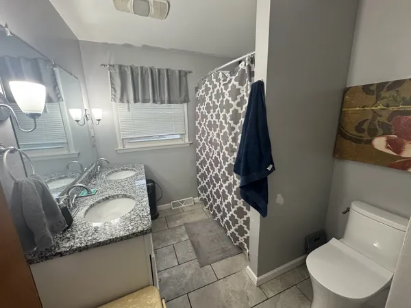 a bathroom with a granite countertop sink a toilet and shower