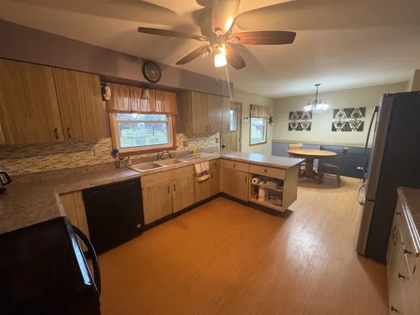 a kitchen with stainless steel appliances a sink a stove a refrigerator cabinets and dining table