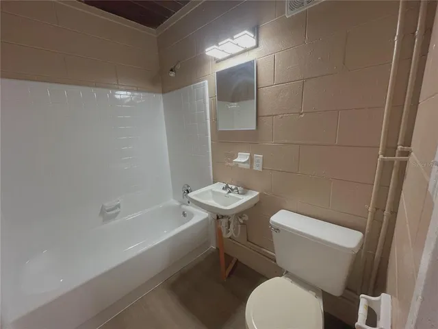 a white toilet sitting next to a bath tub