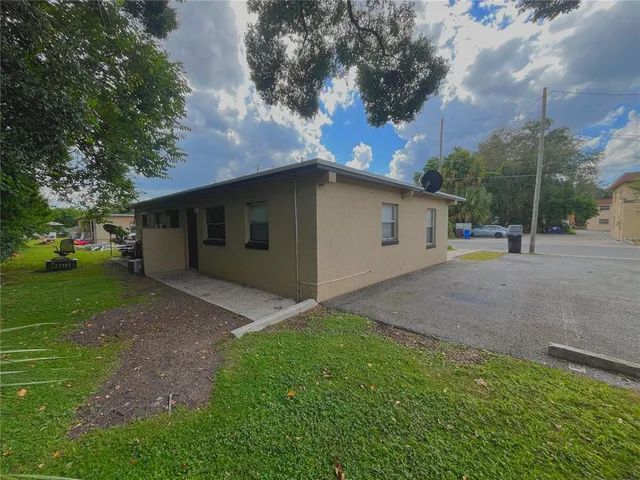 a view of a white house with a yard and large tree