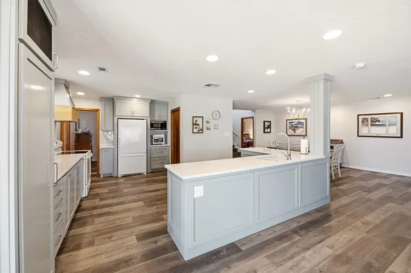 a large white kitchen with a refrigerator a stove top oven and a center island
