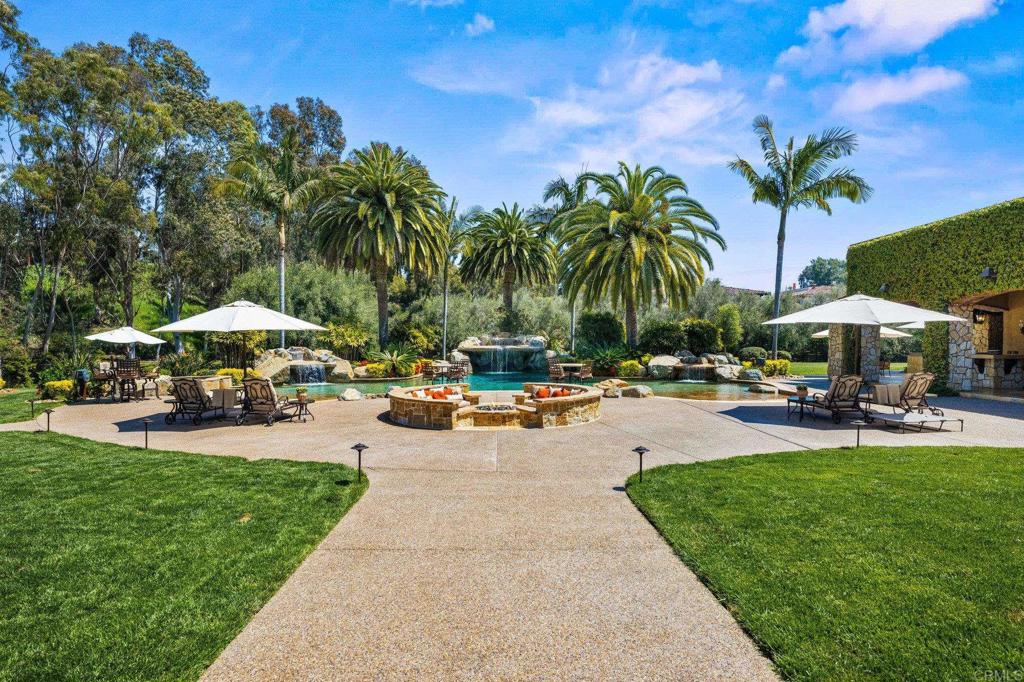 6314 El Apajo Rancho Santa Fe, CA 92067 - Photo 4 of 60 a row of palm trees and a yard with a table and chairs under an umbrella