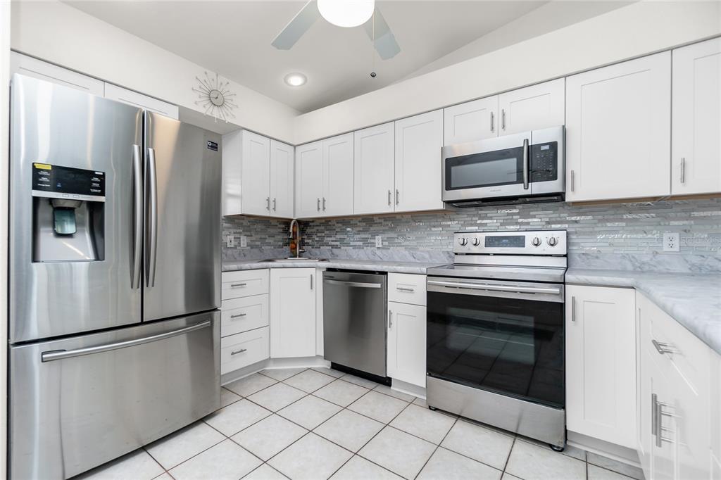 4260 Placida Road, Unit 9B Englewood, FL 34224 - Photo 5 of 38 a kitchen with stainless steel appliances white cabinets white stove a microwave and a refrigerator