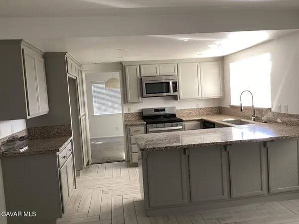 a kitchen with kitchen island granite countertop a sink stove and microwave