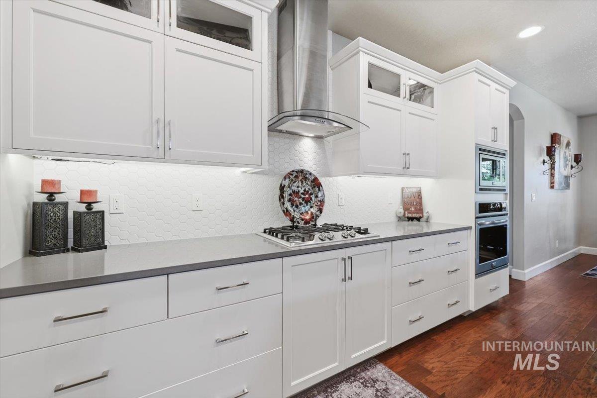 1303 West Brando Street Meridian, ID 83646 - Photo 15 of 49 Well-appointed kitchen featuring white shaker cabinetry, under-cabinet lighting, a hexagonal tile backsplash, a gas cooktop, and built-in wall oven with microwave