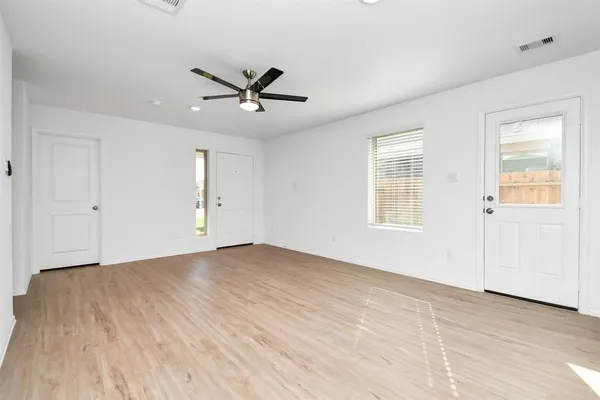a view of empty room with wooden floor and fan