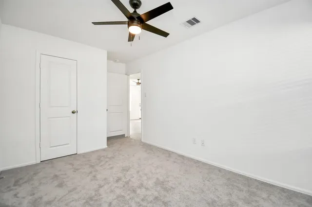an empty room with closet and a ceiling fan