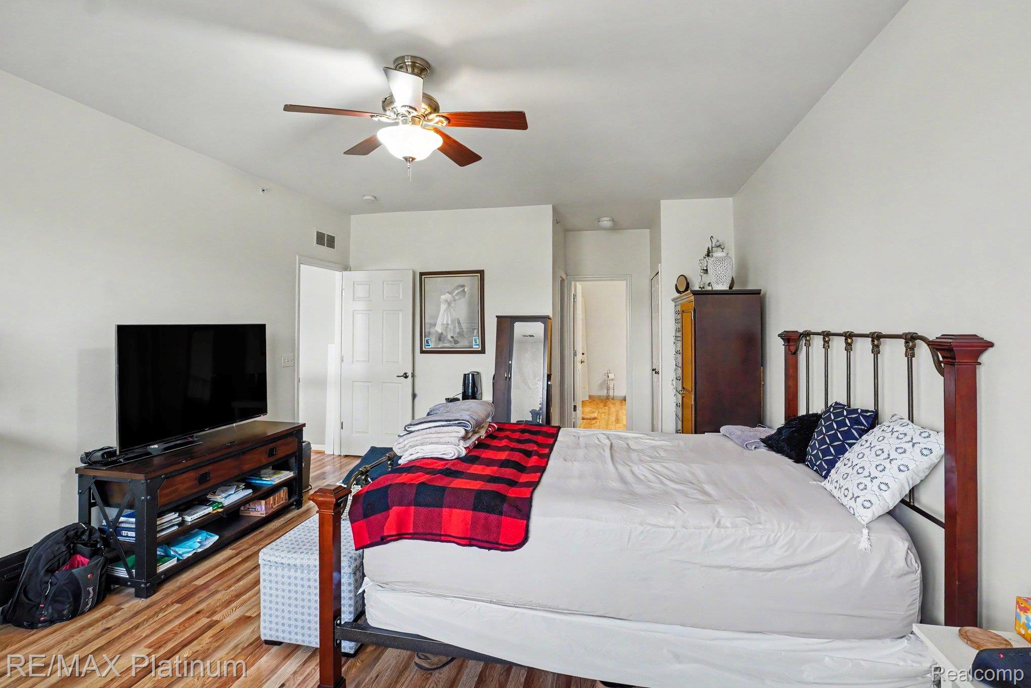 10217 Crossview Trail Howell, MI 48855 - Photo 17 of 26 Bedroom featuring wood-finish flooring, a ceiling fan with integrated lighting, white painted walls, and a multi-panel door