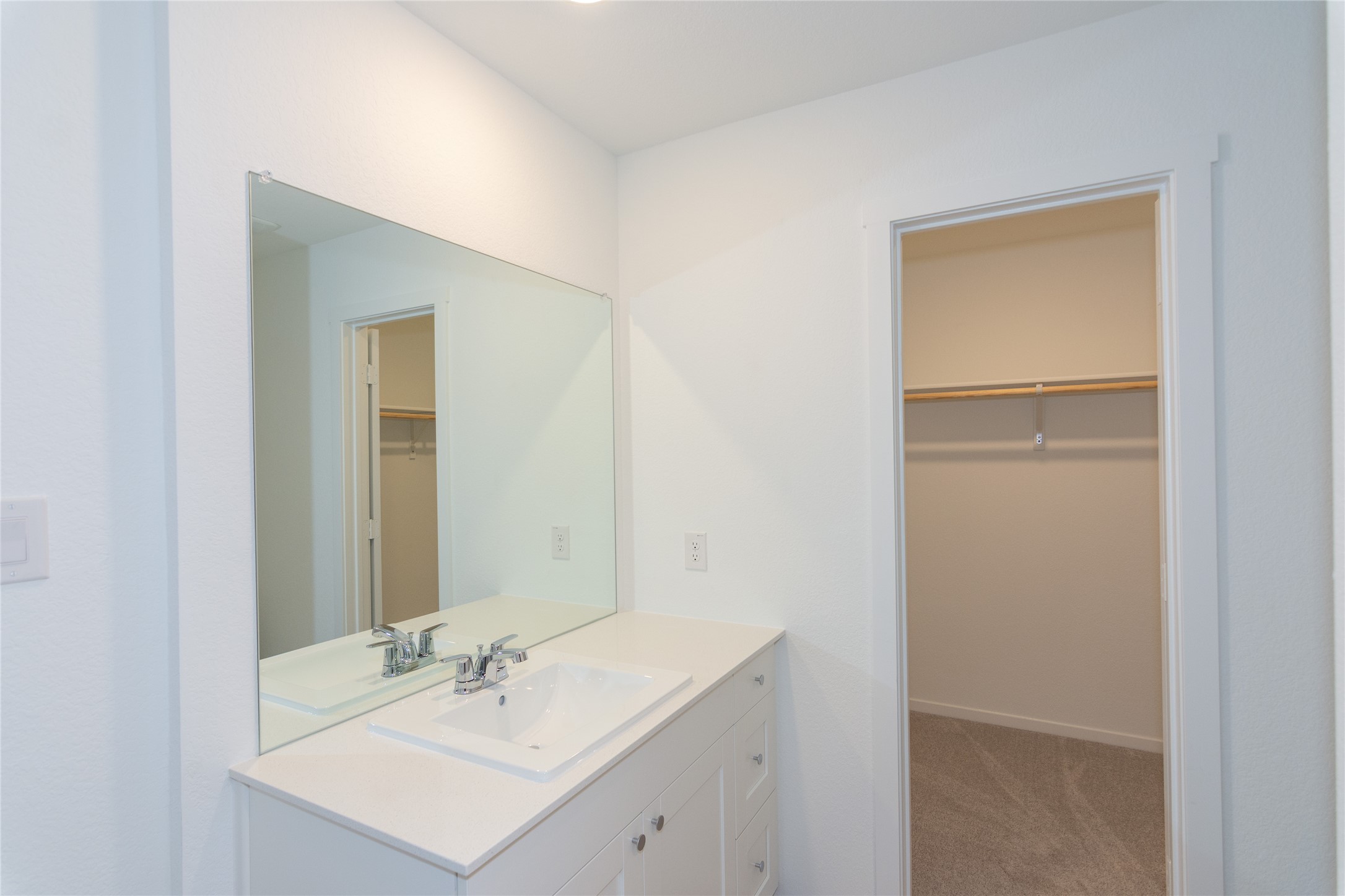149 Star Packer Lane Jarrell, TX 76537 - Photo 15 of 30 A well-appointed bathroom vanity with a clean white counter and an adjacent walk-in closet.