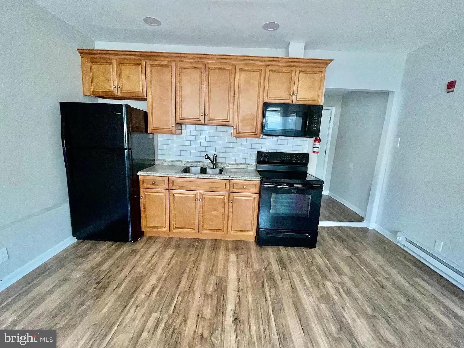5900 Market Street, Unit 3F Philadelphia, PA 19139 - Photo 5 of 9 a kitchen with a refrigerator a stove a microwave and cabinets