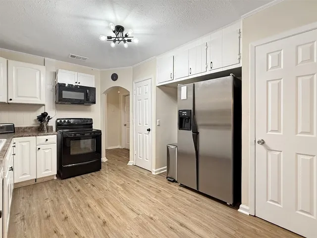 a kitchen with granite countertop a refrigerator stove and microwave