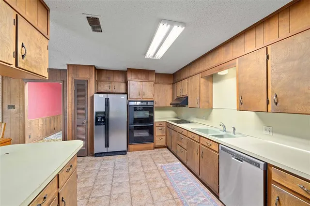 a kitchen with stainless steel appliances granite countertop a refrigerator a sink and a stove