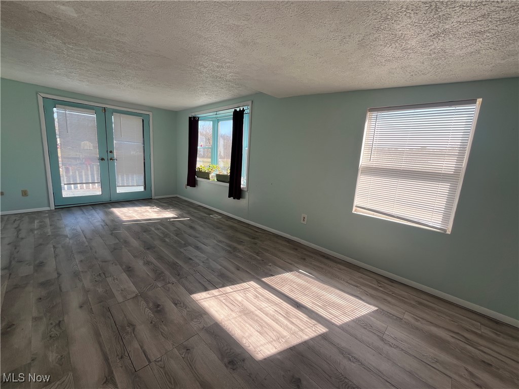 57894 Flamingo Road Senecaville, OH 43780 - Photo 16 of 20 Unfurnished room with french doors, a textured ceiling, baseboards, and wood finished floors