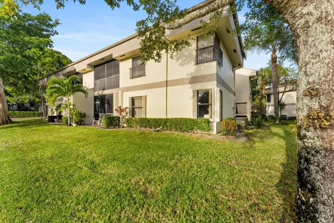 a view of a white house with a big yard and large tree