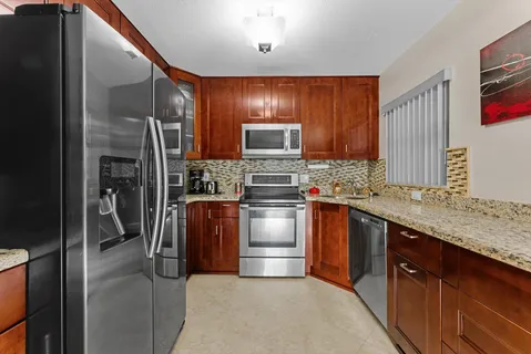 a kitchen with stainless steel appliances granite countertop a refrigerator and a sink