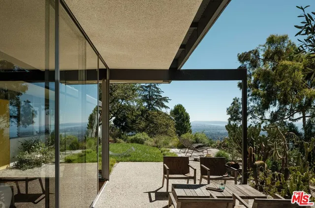 a balcony with table and chairs and potted plants
