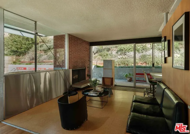 a living room with couches floor to ceiling window and a flat screen tv