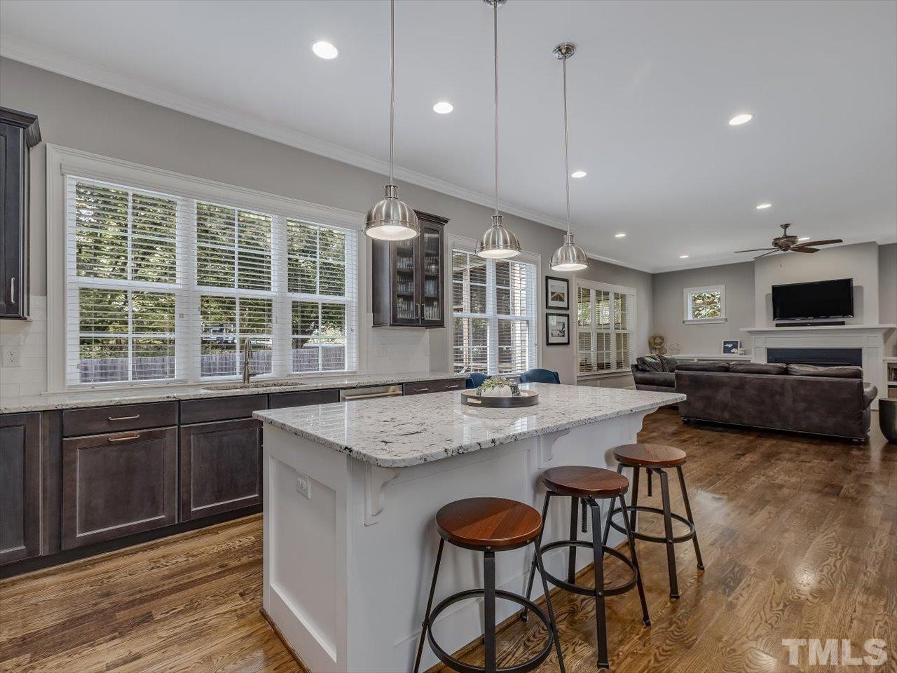 6427 Rosny Road Raleigh, NC 27613 - Photo 23 of 53 a kitchen with stainless steel appliances granite countertop wooden cabinets a stove top oven a sink dishwasher a dining table and chairs with wooden floor