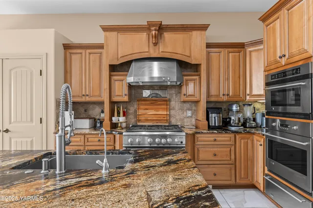 a kitchen with kitchen island granite countertop a stove top oven a sink and dishwasher
