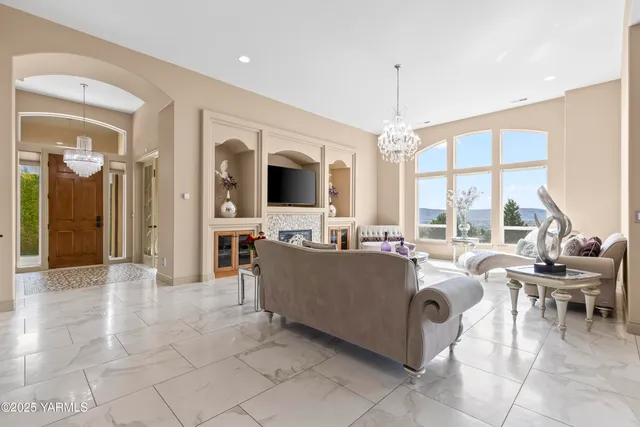 a living room with furniture a large window and a chandelier