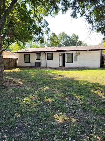 a house that has a big yard large trees with wooden fence