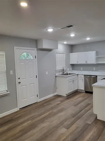 a white kitchen with wooden floors and white cabinets