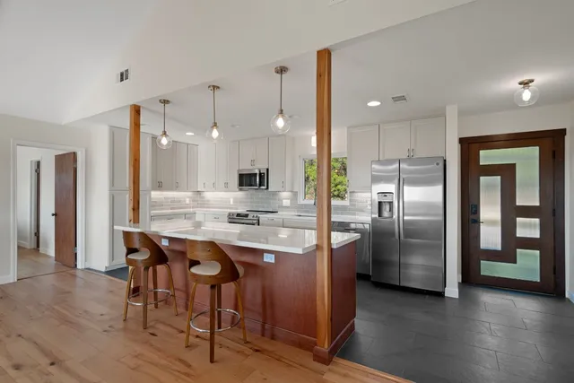 a kitchen with stainless steel appliances granite countertop a refrigerator a sink and a stove